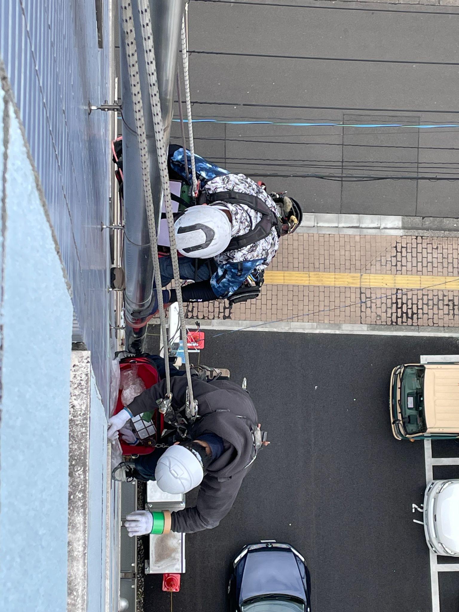 ロープアクセスで外壁の補修をしている様子